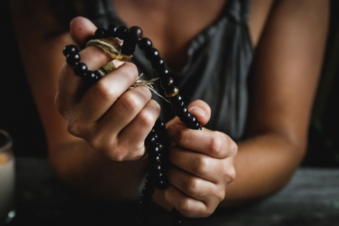 Eine Frau hält einen Rosenkranz in der Hand