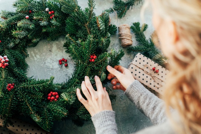 Frau bindet Adventskranz als Adventsdeko