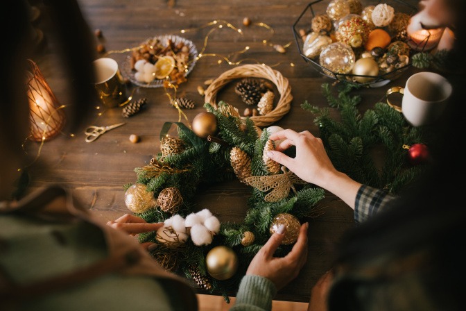 Zwei Personen gestalten einen Adventskranz