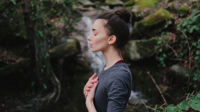 Eine Frau atmet bewusst und ruhig in der Natur