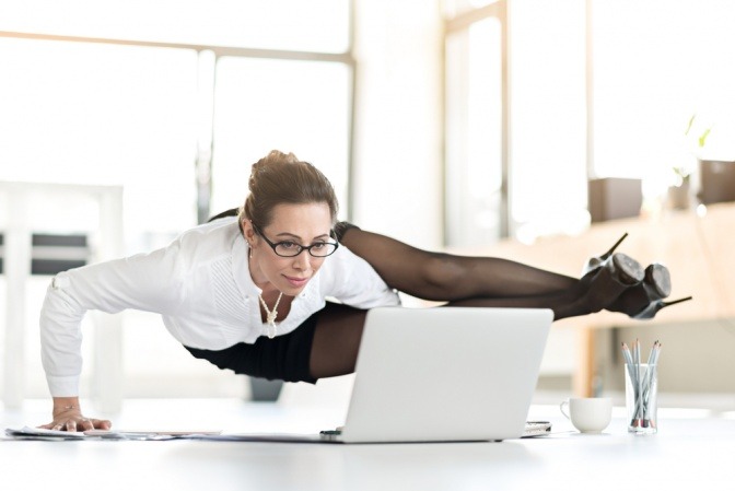 Lächelnde Geschäftsfrau, die Yoga im Büro macht. 