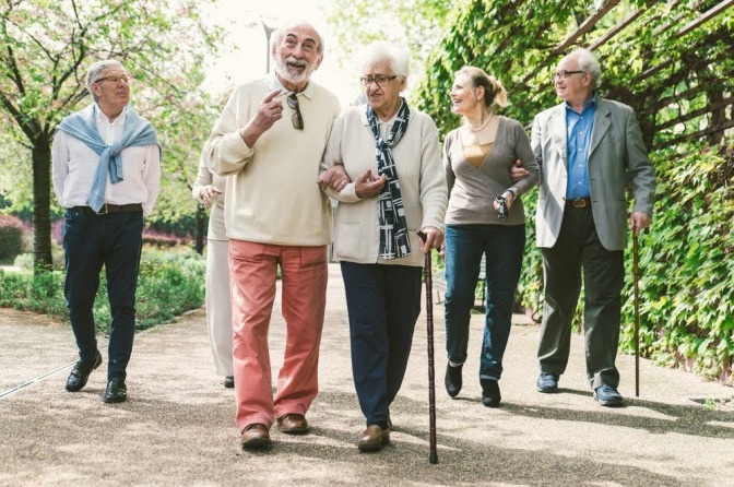 Mehrere Paare in unterschiedlichen, aber eher hohen Altersgruppen machen einen Spaziergang durch einen Park.