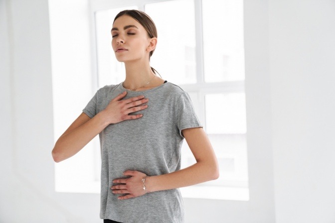 Frau macht Atemübung gegen Stress im Stehen.