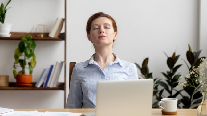 Frau im Büro macht Atemübungen gegen Stress