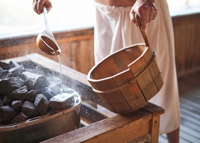 Ein Mann macht einen Aufguss in der Sauna mit ätherischen Ölen