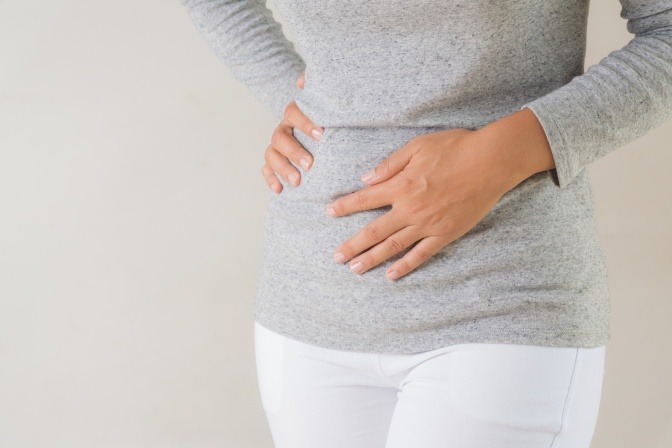 Eine Frau hält ihre Hand auf den Bauch als Zeichen für eine Bauchstraffung