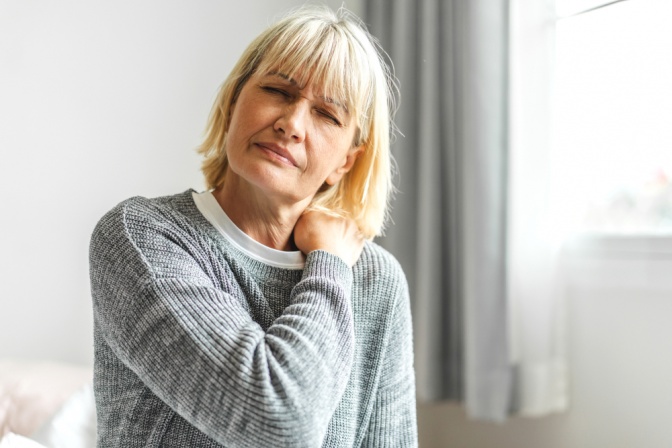 Frau hält sich den Nacken