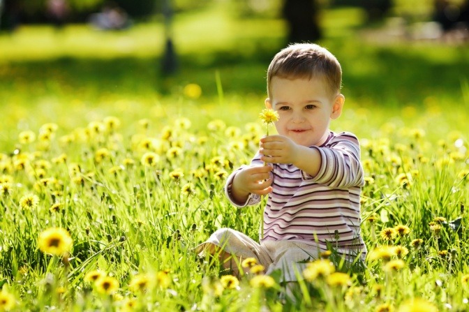 Ein Bub sitzt im Gras