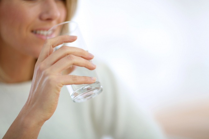 Frau trinkt Wasser als calciumhaltiges Lebensmittel