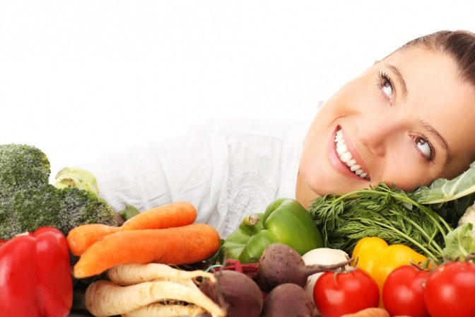 Eine Frau lehnt glücklich zwischen Obst, da sie faltenfrei durch Ernährung ist