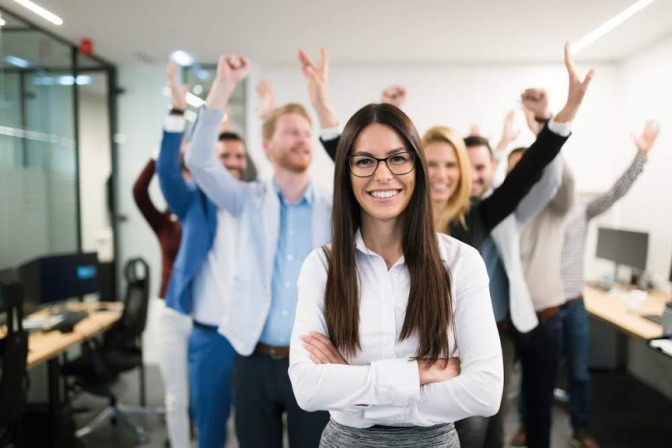 Hinter einer Frau in der Führungsrolle steht ein jubelndes Team