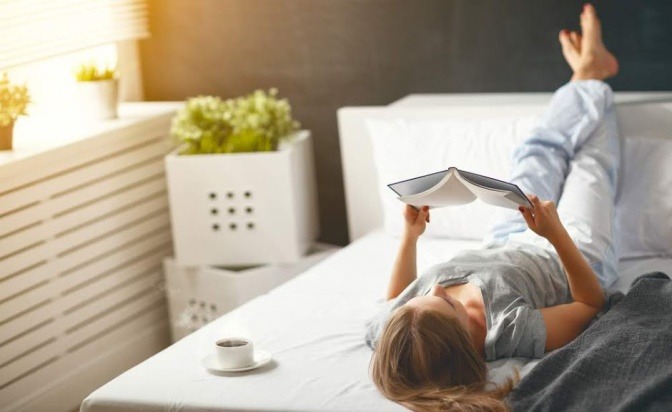 Eine Frau liegt im Bett und liest ein Buch