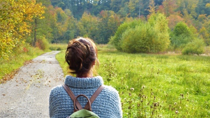 Eine Frau steht in einer sonnenbeschienenen Landschaft