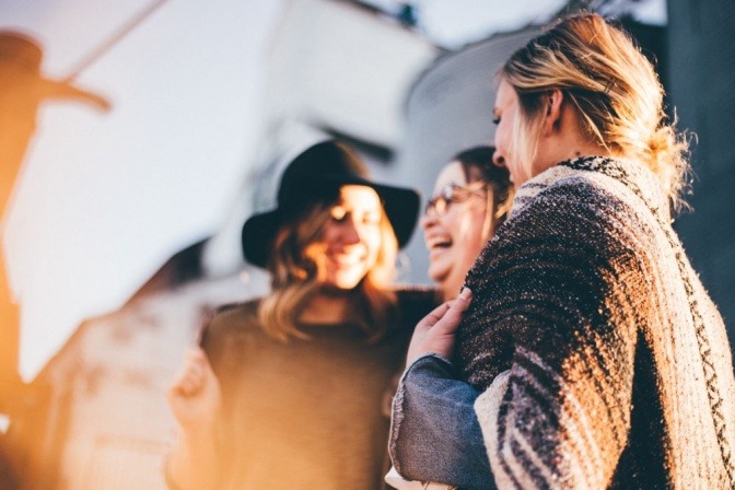 Drei Frauen stehen eng nebeneinander und lachen herzlich