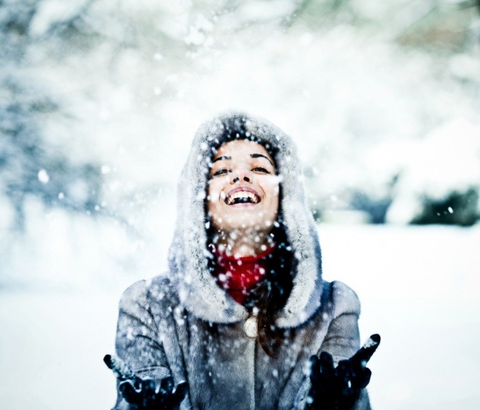 Eine Frau steht mit Winterjacke im Schnee