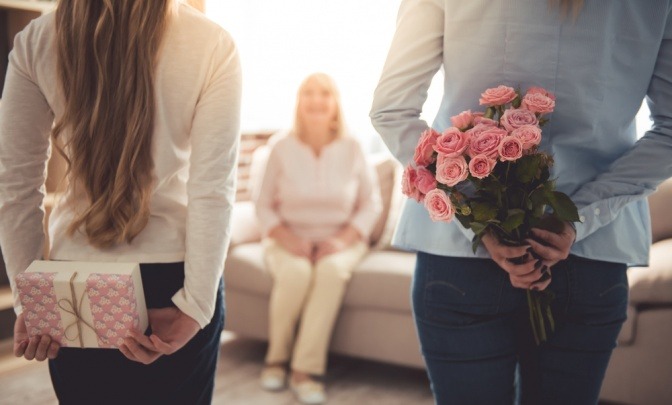 Eine Mutter und ihre Tochter verstecken Geschenke hinter ihrem Rücken