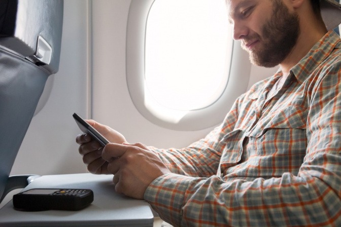 Mann mit einem Handy im Flugzeug