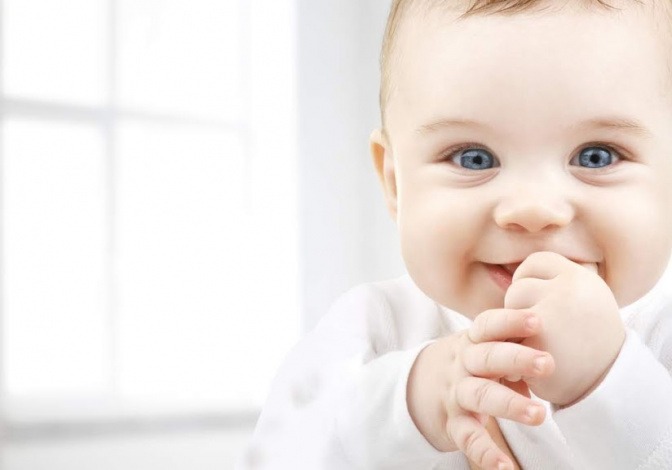 Ein Baby mit strahlend blauen Augen lacht über das ganze Gesicht