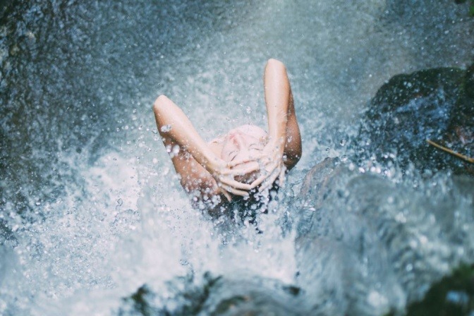 Eine Frau wäscht in der Natur ihre Haare nur mit Wasser