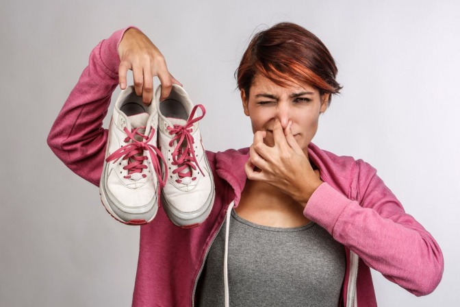 Frau mit Schuhen in der Hand hält die Nase zu