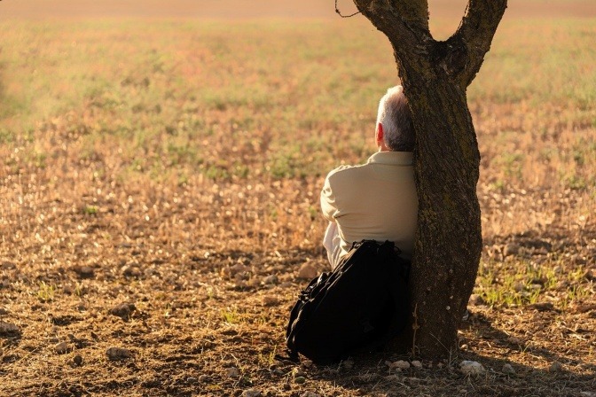 Ein immunstarker Mann sitzt im Herbst an einen Baum gelehnt