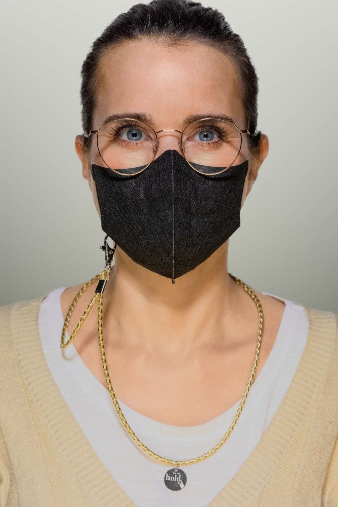 Eine Frau trägt eine Maske mit einem Holdie Maskenband 