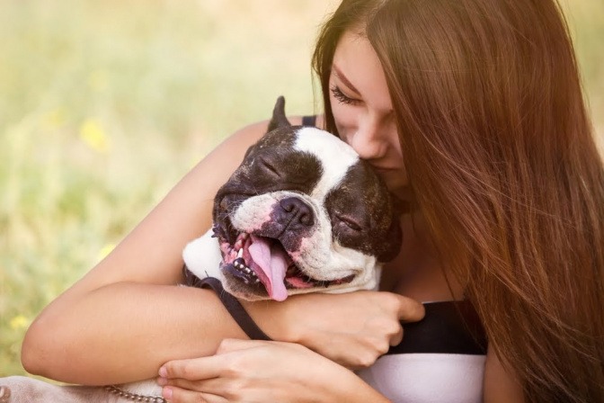 Eine Frau kuschelt mit ihrem Hund.