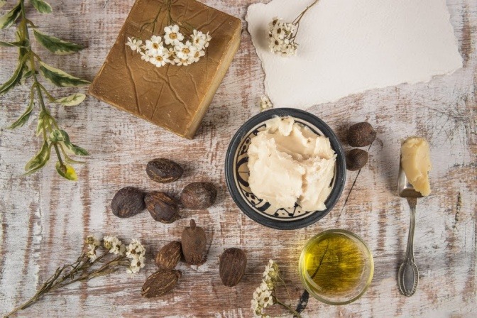 Sheabutter ist angerichtet, daneben liegen Nüsse