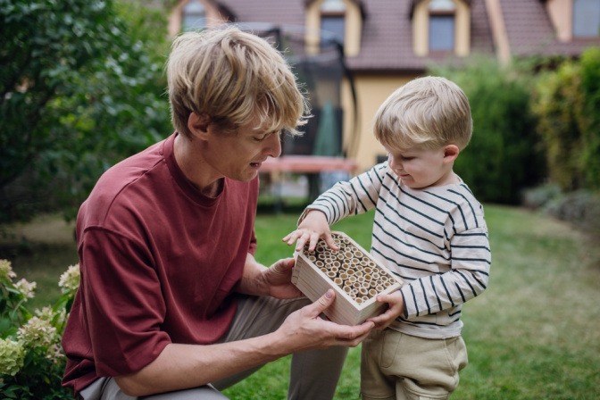 Vater zeigt seinem Kind Material für Insektenhotel.