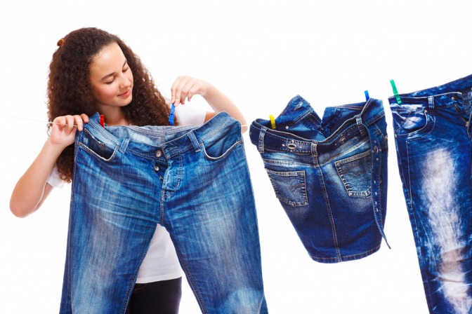 Frau hängt Jeanshosen zum Trocknen auf eine Wäscheleine auf.