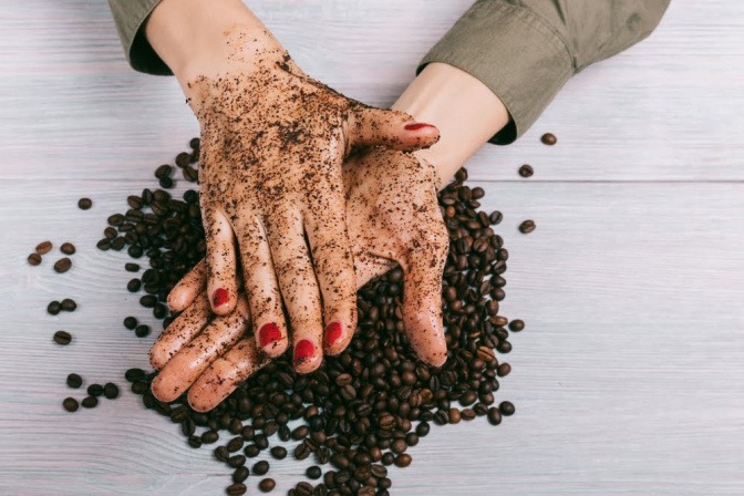 Hände reiben ein Kaffee-Peeling 