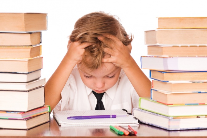 Ein kleines Kind sitzt zwischen zwei Stapeln mit Büchern als Ursache für Burnout