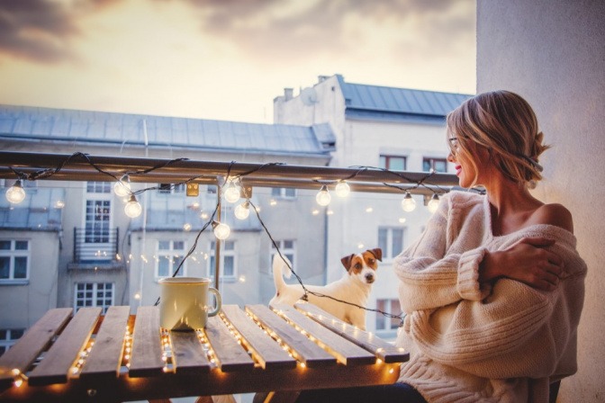 Romantische Balkonbeleuchtung - Frau sitzt bei Sonnenuntergang auf Balkon