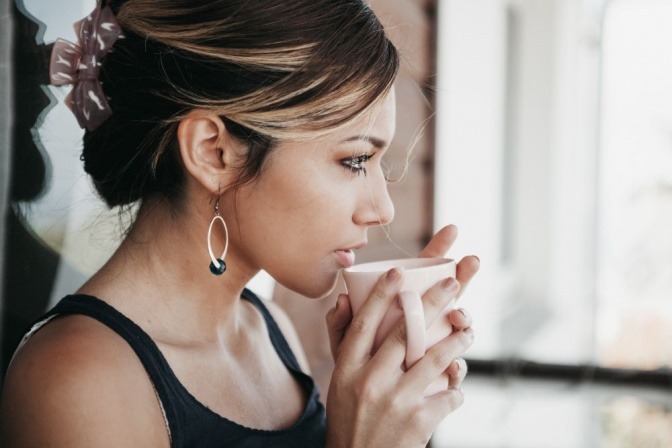 Eine Frau trinkt Kaffee, in dem Koffein enthalten ist