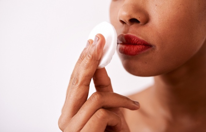 Frau entfernt Lippenstift mit einem Wattepad