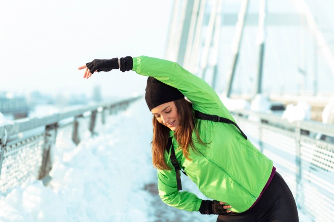 Junge Frau im Winter beim Dehnen.