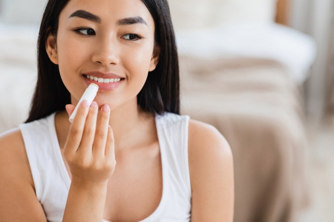 Eine Frau pflegt ihre trockenen Lippen mit einem Lippenstift