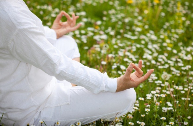 Frau in weiß in Meditationshaltung am Boden im Lotussitz