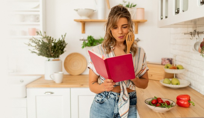 Frau sucht in einem Kochbuch nach Low Carb Rezepten