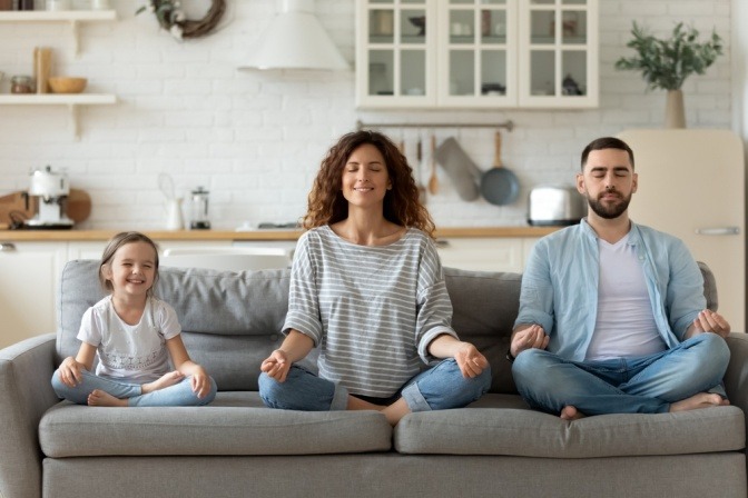 Eine kleine Familie meditiert auf der Couch als Morgenritual