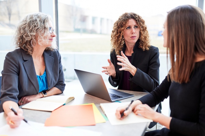 Ein Arbeitsmeeting. Eine Frau legt ihre Position gestikulierend dar.