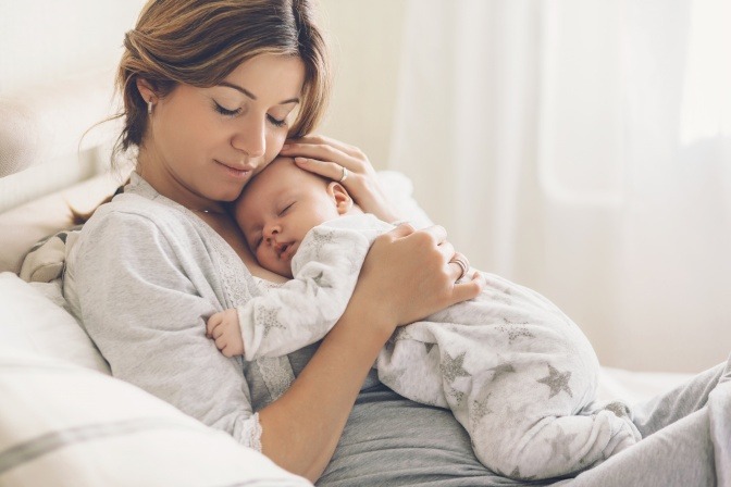 Eine Frau hält ihr Baby und denkt über ein Mommy Makeover nach