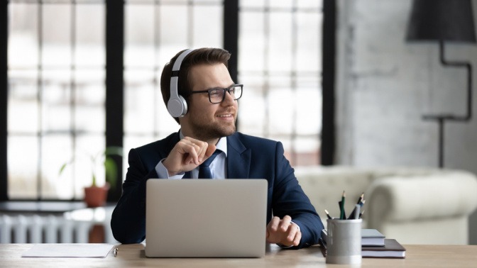 Ein Mann im Anzug hört auf der Arbeit mit Kopfhörern Musik