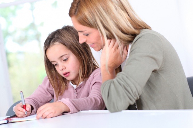 Eine Mutter sitzt mit ihrer Tochter beim Lernen