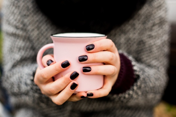 Hände mit schwarzem Nagellack.