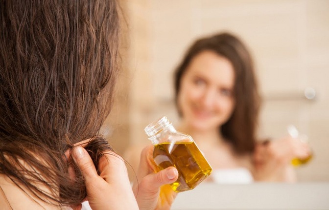 Eine Frau gibt Olivenöl auf die Haare