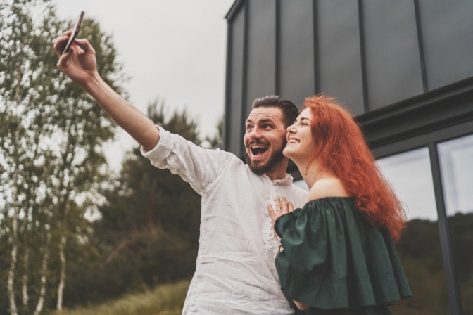 Bärtiger Mann und rothaarige Frau, die sich im Internet kennengelernt und verliebt haben, machen ein Selfie.