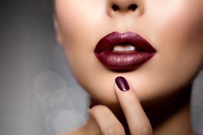 Eine Frau hat rote Lippen in der Trendfarbe Oxblood