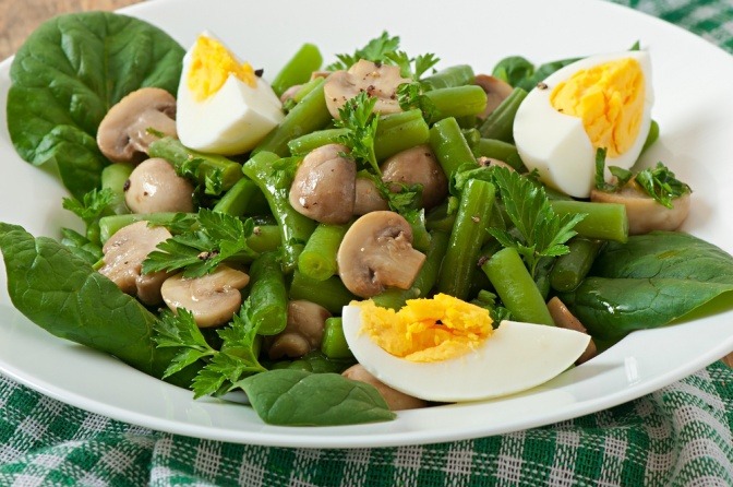 Pilze, Hülsenfrüchte und Eier liegen mit Salat auf einem Teller