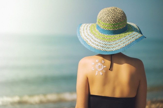 Frau mit Sonnencreme auf dem Rücken